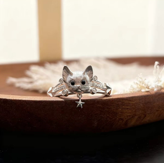 Front view of a 925 sterling silver cat ring with a hanging star pendant resting on a wooden display tray.