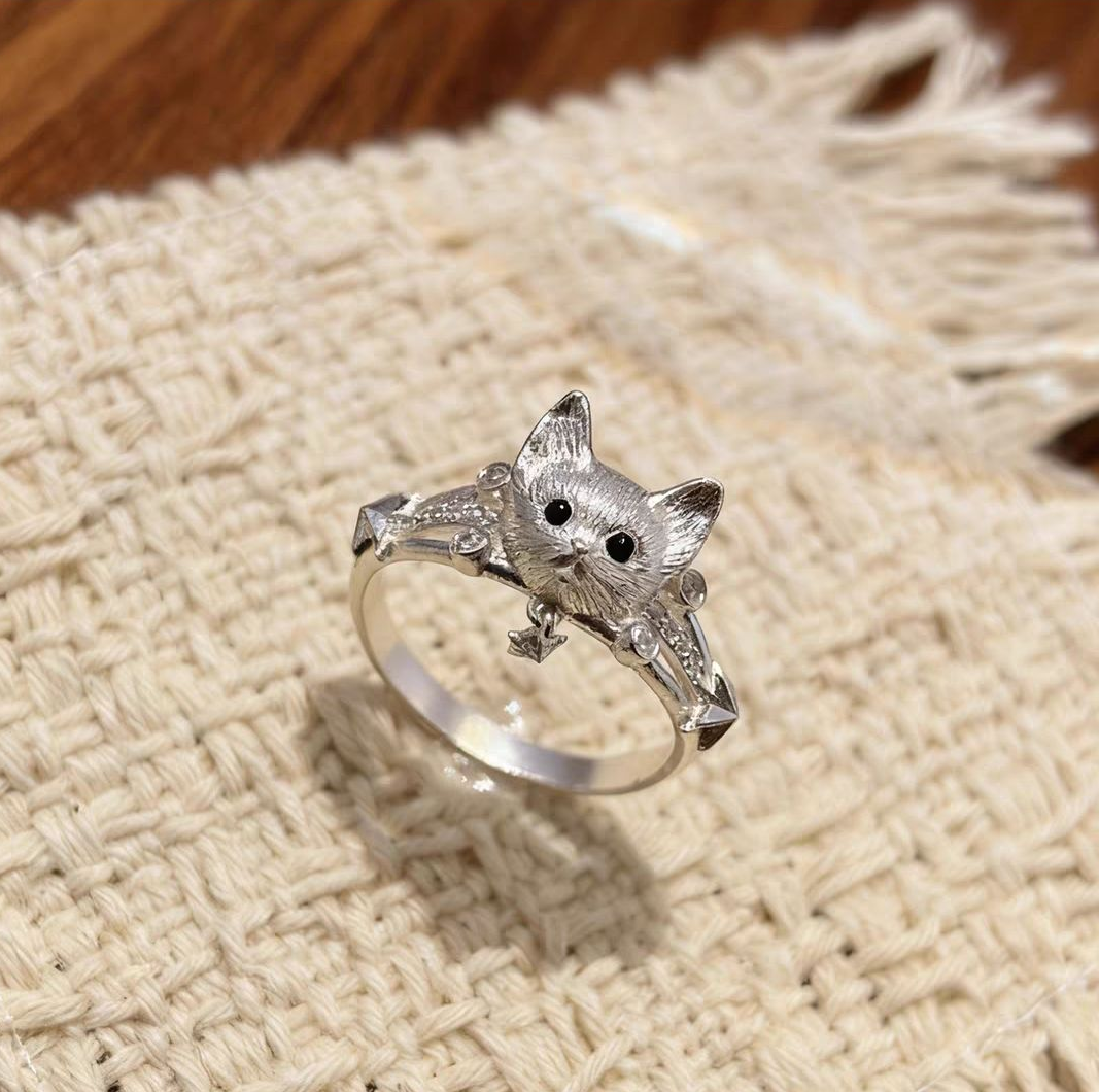 A 925 sterling silver cat ring featuring a small star charm displayed on natural woven linen background.