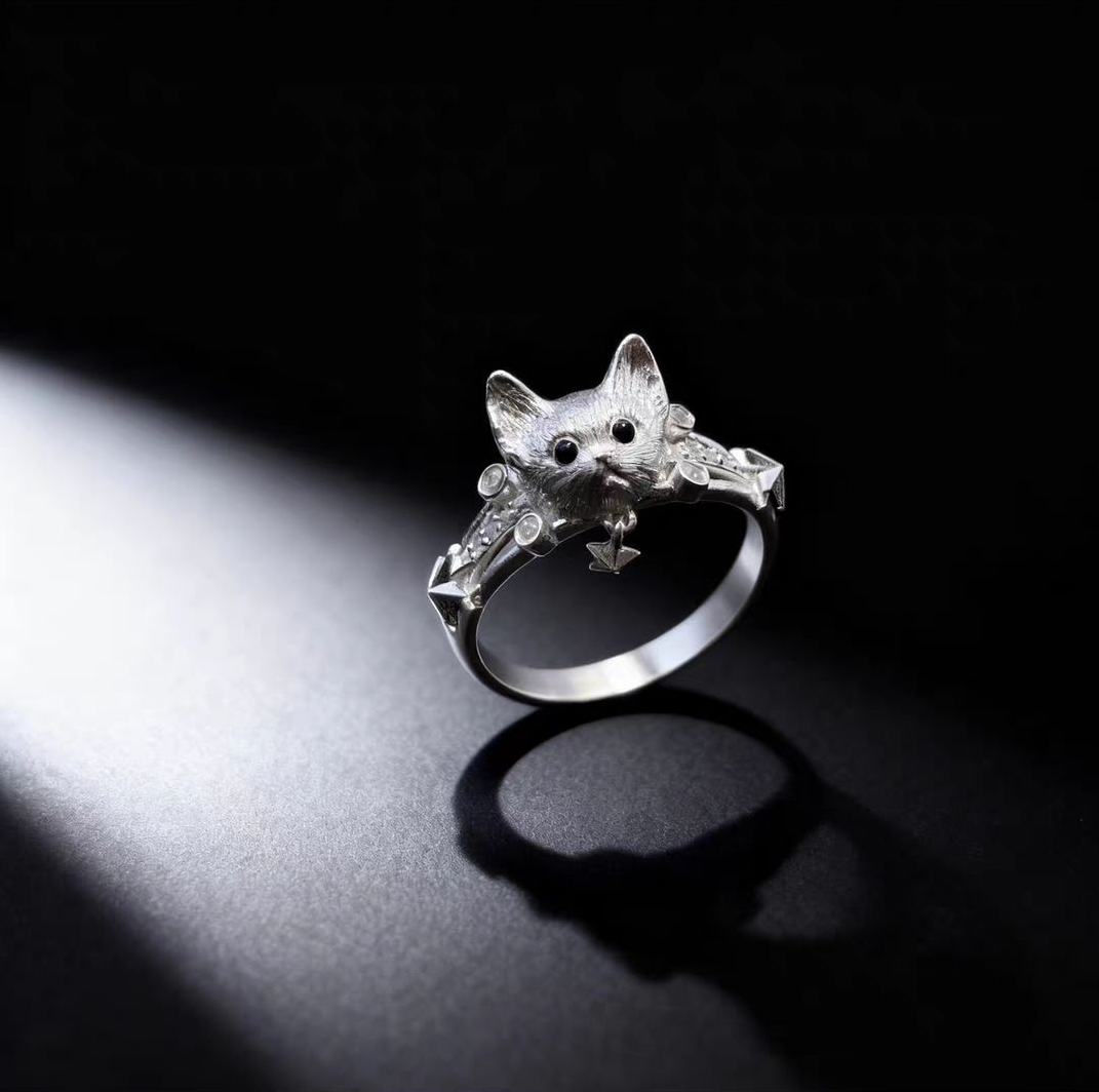 Dramatic close-up product shot of a 925 sterling silver cat face ring with star pendant on a black background.
